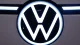 Close-up of a glowing Volkswagen circular logo on a car, dark background around it.