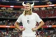 Athlete in a white soccer jersey with number 9 poses with hands on hips, wearing a Viking helmet on a crowded stadium field.