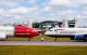 Two passenger planes from Norwegian (red) and British Airways (white/blue) sit nose-to-nose on a runway with a soccer ball between them.