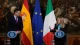 Two politicians at separate podiums with flags (Spain, EU, Italy) behind them during a formal press conference.
