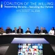 Global summit of officials seated at a long curved table on a blue backdrop with flags, Kyiv 2026 signage behind them.