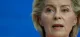 Close-up of a woman speaking, set against a solid blue background.