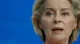 Close-up of a woman speaking, set against a solid blue background.