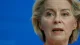Close-up of a woman speaking, set against a solid blue background.