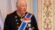 Older man in a ceremonial military uniform with epaulettes and medals at a formal ceremony.