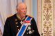 Older man in a ceremonial military uniform with epaulettes and medals at a formal ceremony.