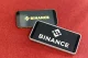Two smartphones displaying the Binance logo on a red surface