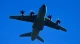 Military transport aircraft flying against a clear blue sky