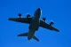 Military transport aircraft flying against a clear blue sky