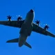 Military transport aircraft flying against a clear blue sky